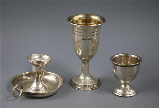 A modern silver goblet, silver egg cup and silver chamberstick.